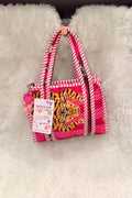 A small pink and white striped fabric handbag with a tiger face patch on the front, hanging on a white faux fur surface. The bag has pink-and-white striped handles, a pink and white striped zipper pull, and a hanging paper tag that reads 'DESVANI'.